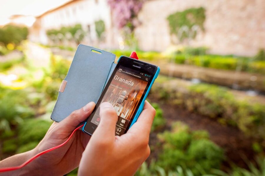 A phone held up on a garden path, audio guide running